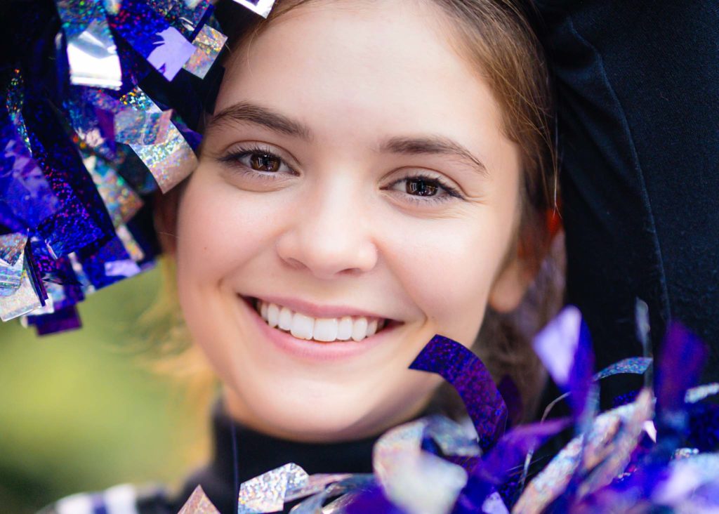 girl cheerleading with purple pom poms for senior photoshoot